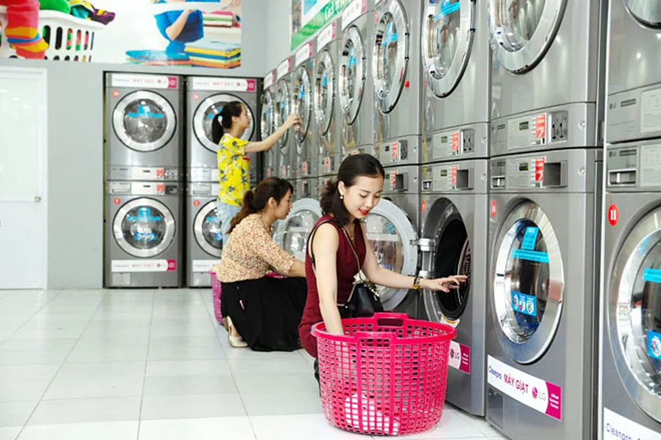 Dãy máy giặt và máy sấy cửa trước hoạt động liên tục trong tiệm giặt