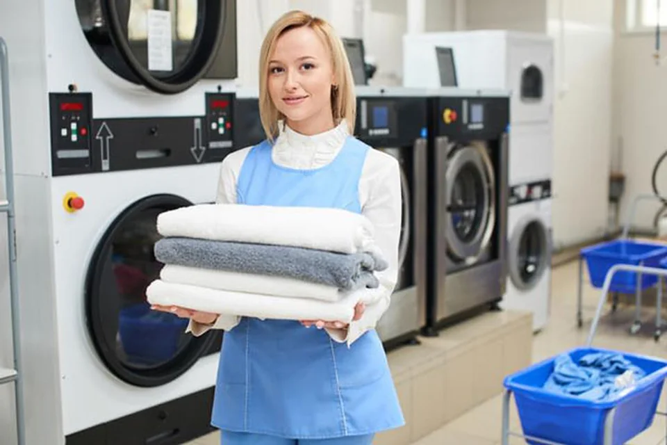 Nhân viên bàn giao khăn tắm vừa sấy khô được gấp gọn